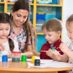 teacher helping children paint